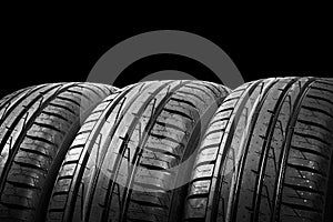 Studio shot of a set of summer car tires isolated on black background. Tire stack background. Car tyre protector close up. Black r