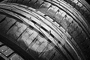 Studio shot of a set of summer car tires isolated on black background. Tire stack background. Car tyre protector close up. Black r
