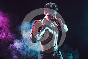 Studio shot of shirtless boxer fighter who preparing for fight on smoke background. Sport concept