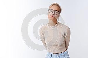 Studio shot of silly glamour cute blond woman 25s in glasses and cropped sweater folding lip bending forward sending