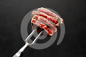 Studio shot of slices of steak on a meat fork