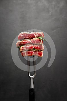 Studio shot of slices of steak on a meat fork