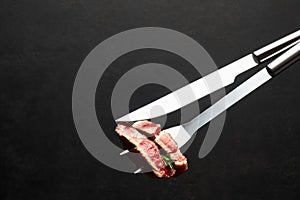 Studio shot of slices of steak on a meat fork