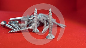 Small hex head screws on a red background
