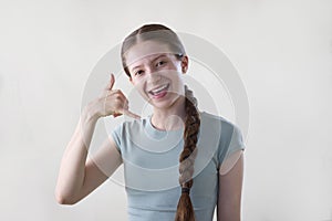 Studio Shot Of Smiling Teenage Girl Making Call Me Gesture Looking Into Camera