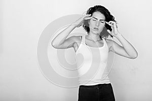 Studio shot of stressed teenage girl having headache against green painted wall