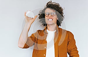 Studio shot of stressed unhappy man scream at someone, take crumpled paper can`t control emotions, wearing round spectacles,