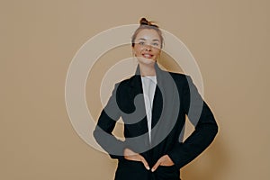 Studio shot of stylish caucasian female model in black suit with hair tied up in high bun