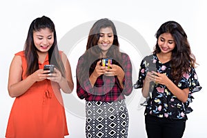 Studio shot of three happy young Persian woman friends smiling w