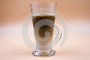 Studio shot of three layered tea in a clear glass with orange ombre background