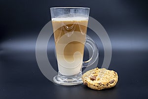Studio shot of three layered tea drink with a chocolate chip cookie in black ombre background
