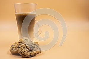 Studio shot of three layered tea drink and chocolate chip cookies in orange ombre background