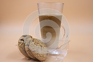 Studio shot of three layered tea drink and chocolate chip cookies in orange ombre background