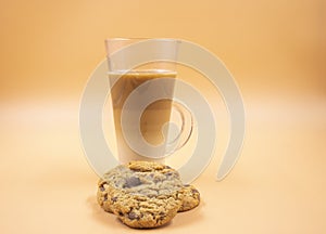 Studio shot of three layered tea drink and chocolate chip cookies in orange ombre background
