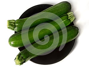 Studio shot of three zucchinis on black plate - isolated on white