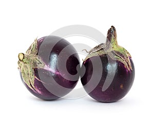 Studio shot of two organic violet round Thai eggplant isolated on white