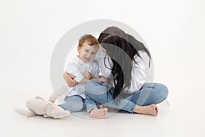 Studio shot of two people, woman and boy having fun and sitting, talking to each other. Happy family. White background