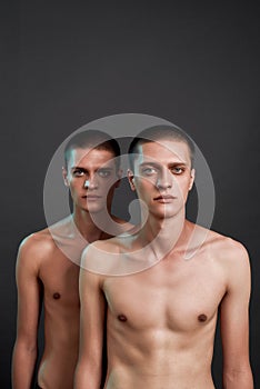 Studio shot of two young caucasian half naked twin brothers looking at camera while posing in studio, standing isolated