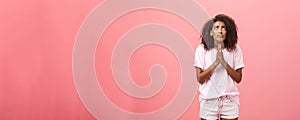 Studio shot of unhappy miserable and hopeless cute african american female holding hands in pray near chest looking up