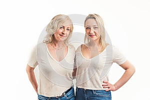 Studio shot on white background of two similarly looking middle-aged women, standing close to each other placing their
