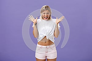 Studio shot of woman having mental breakdown screaming out loud shaking raised palms closing eyes and bending head down