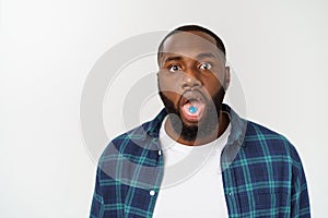 Studio shot of young African American man with candy in mouth against gray background