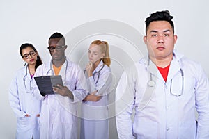 Studio shot of young Asian man doctor with diverse group of mult