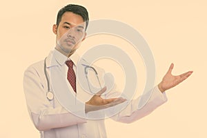Studio shot of young Asian man doctor showing something