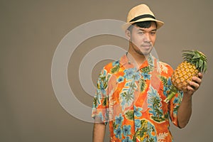 Young Asian tourist man ready for vacation against gray background