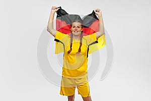Studio shot of young astonished girl with german national flag supports favorite team. Soccer fans, emotions