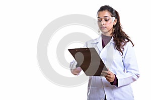 Studio shot of young beautiful Indian woman doctor reading on cl