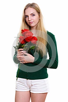 Studio shot of young beautiful teenage girl holding red roses re