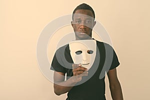 Studio shot of young black African man holding mask