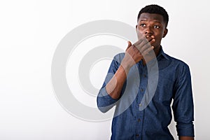 Studio shot of young black African man thinking and looking shoc