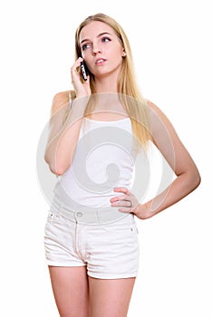 Studio shot of young bored teenage girl talking on mobile phone