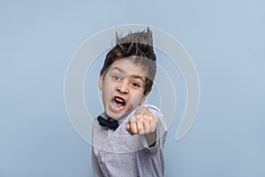 Studio shot of a young boy  reading to fend for himself, his fist is ready for battle on against blue background  with copy space