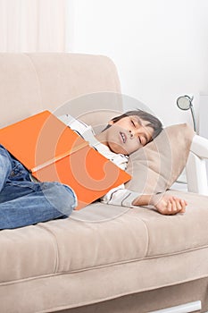 Studio shot of a young boy wearing a white shirt and jeans with headphones siting on the floor by the wall and thinks or sad about