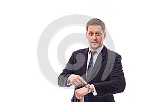 Studio shot of a young businessman wearing dark blue suit points to time on a wristwatch recalling the necessary discipline or