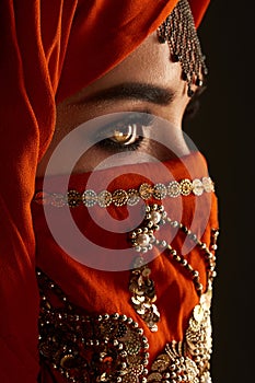 Studio shot of a young charming woman wearing the terracotta hijab decorated with sequins and jewelry. Arabic style.