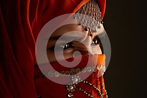 Studio shot of a young charming woman wearing the terracotta hijab decorated with sequins and jewelry. Arabic style.
