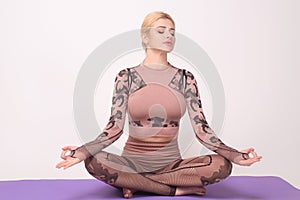 Studio shot of a young fit woman doing yoga exercises. Sporty fit and slim female fitness model in pose lotus. Fit woman