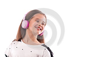 Studio shot of a young girl wearing white blouse on a white background. She is standing in pink headphones listening to music