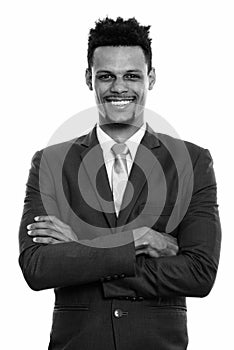 Studio shot of young happy African businessman smiling with arms crossed