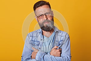  studio shot of young handsome bearded hipster man wearing trendy denim jacket, looking serious and pensive directly at