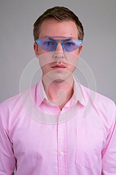 Face of young handsome businessman wearing blue novelty glasses