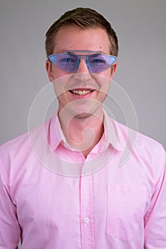 Face of young happy businessman smiling while wearing blue novelty glasses