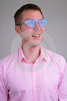 Face of young happy businessman thinking with blue novelty glasses