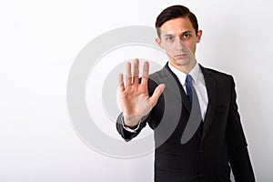 Studio shot of young handsome businessman showing stop hand sign