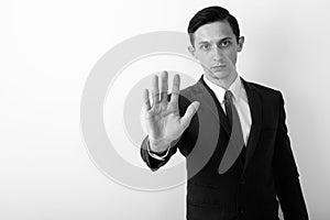 Studio shot of young handsome businessman showing stop hand sign against white background
