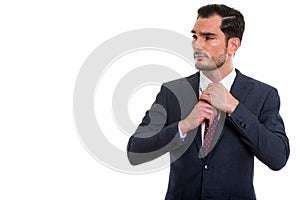 Studio shot of young handsome businessman thinking and looking a